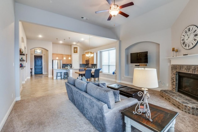 living room with light colored carpet, baseboards, ceiling fan with notable chandelier, a brick fireplace, and visible vents