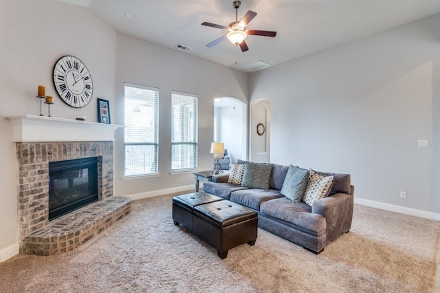 living area with a fireplace, carpet flooring, visible vents, and ceiling fan