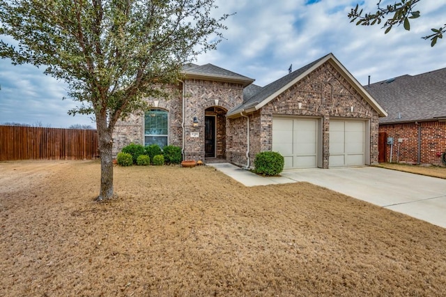 view of front of house featuring brick siding, driveway, fence, and a garage