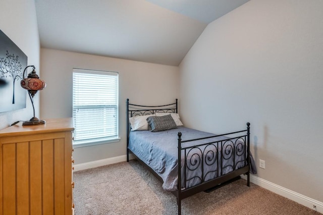 bedroom with baseboards, vaulted ceiling, and light colored carpet