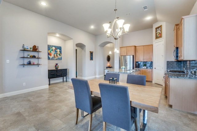 dining area featuring vaulted ceiling, baseboards, arched walkways, and an inviting chandelier