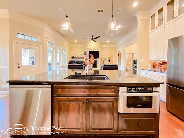 kitchen with a center island with sink, stainless steel appliances, light countertops, glass insert cabinets, and white cabinets