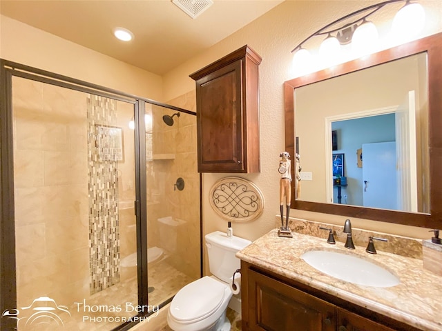 bathroom with visible vents, a textured wall, toilet, vanity, and a shower stall