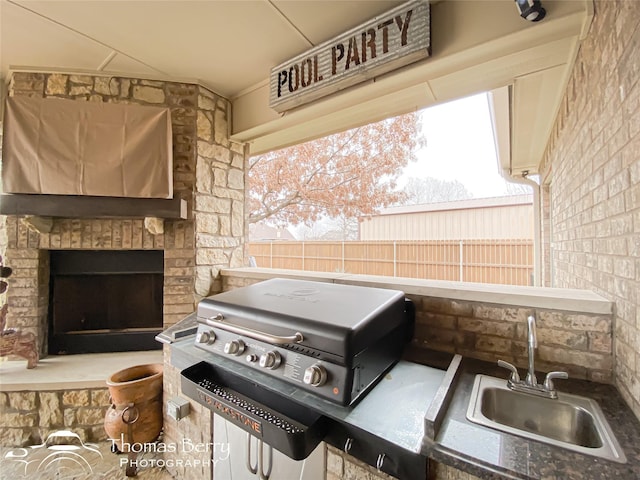 view of patio with area for grilling, a fireplace, a sink, fence, and grilling area