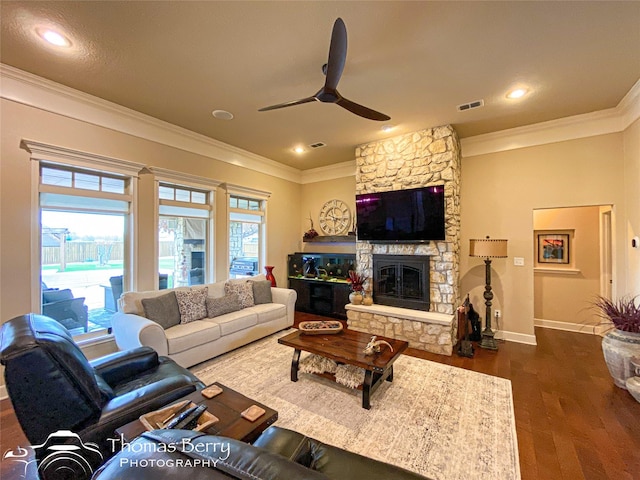 living room featuring dark wood-style floors, a fireplace, visible vents, and crown molding