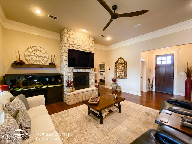 living room featuring dark wood-style floors, visible vents, and a stone fireplace