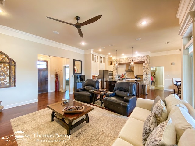 living room with recessed lighting, dark wood-type flooring, a ceiling fan, baseboards, and crown molding