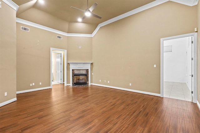 unfurnished living room with a high end fireplace, ceiling fan, wood finished floors, and visible vents