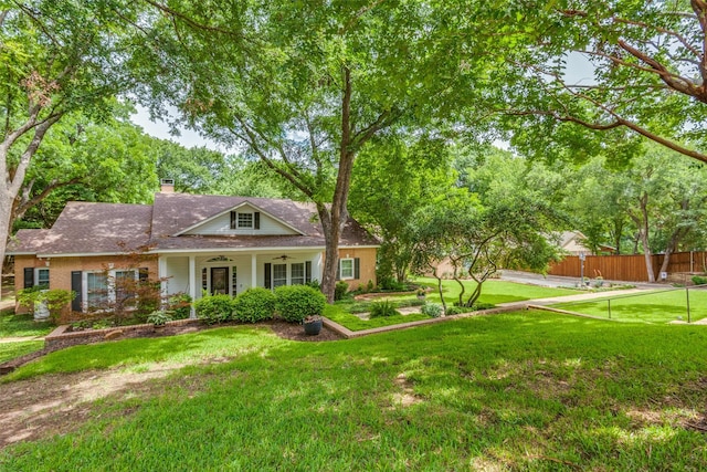 exterior space with ceiling fan, a chimney, a front lawn, and fence