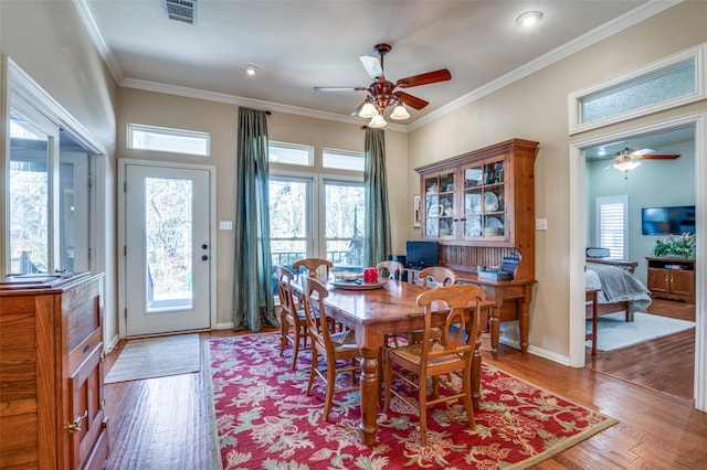 dining space with ornamental molding, ceiling fan, wood finished floors, and visible vents