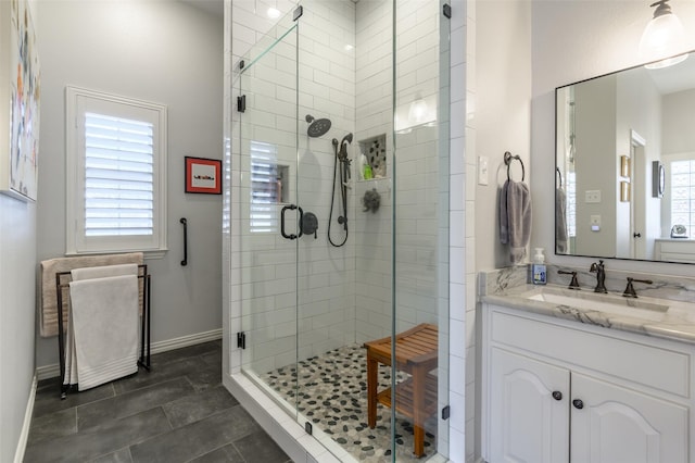 full bath with vanity, baseboards, and a shower stall