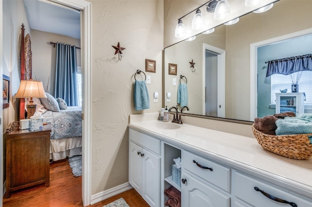 bathroom with baseboards, vanity, wood finished floors, a textured wall, and ensuite bath