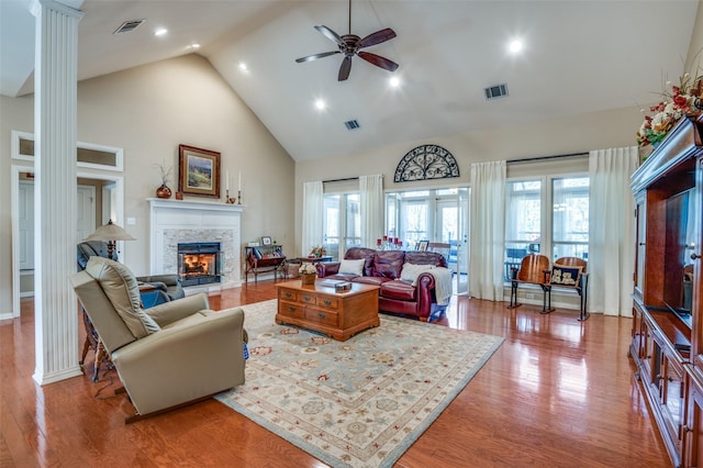 living room with plenty of natural light, decorative columns, a stone fireplace, and visible vents