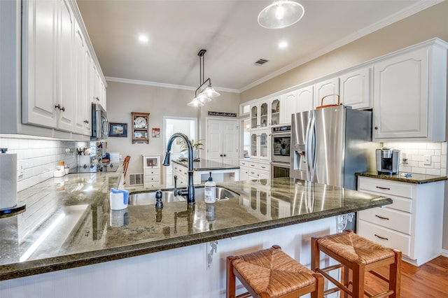 kitchen with a breakfast bar area, stainless steel appliances, a peninsula, and hanging light fixtures