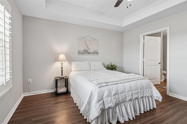 bedroom featuring dark wood-style flooring, a ceiling fan, baseboards, a tray ceiling, and crown molding