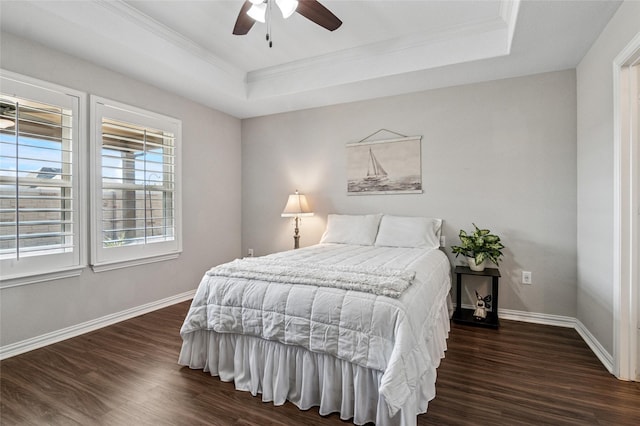 bedroom with dark wood-style floors, a raised ceiling, and baseboards