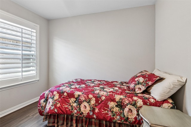 bedroom featuring multiple windows, baseboards, and wood finished floors