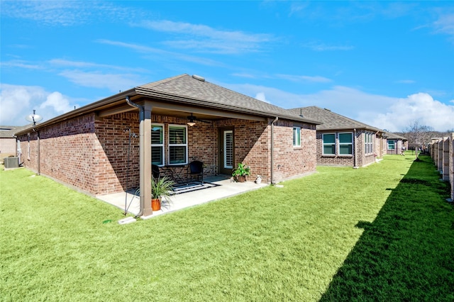 rear view of house with a lawn, fence, central air condition unit, a patio area, and brick siding