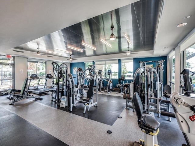 exercise room featuring visible vents, a raised ceiling, and a ceiling fan