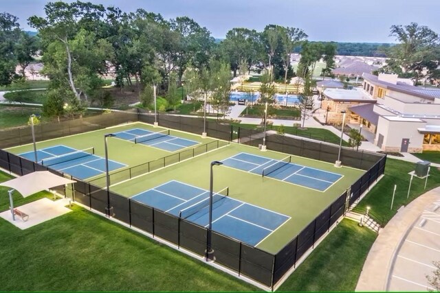 view of tennis court with fence and a yard