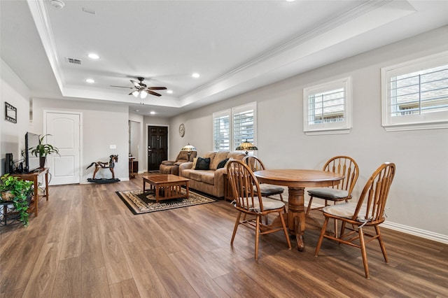 dining room featuring visible vents, a tray ceiling, wood finished floors, and ornamental molding