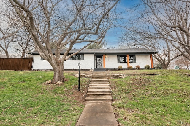 mid-century inspired home with brick siding, fence, and a front yard