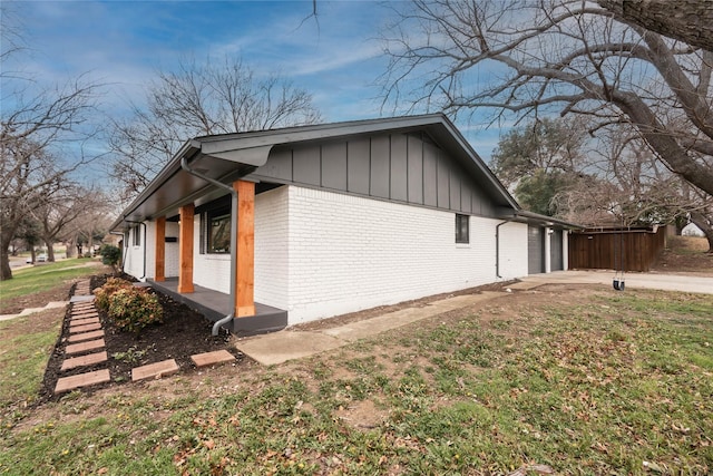 view of property exterior with covered porch, driveway, brick siding, and board and batten siding