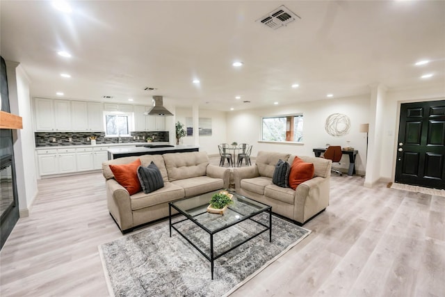 living room featuring light wood-type flooring, visible vents, baseboards, and recessed lighting