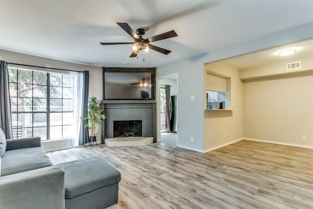 living room with light hardwood / wood-style flooring, a fireplace, and ceiling fan