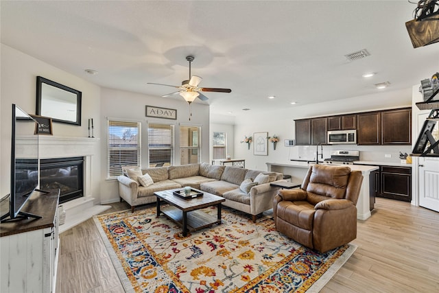 living room featuring ceiling fan, a fireplace, light wood-style flooring, recessed lighting, and visible vents