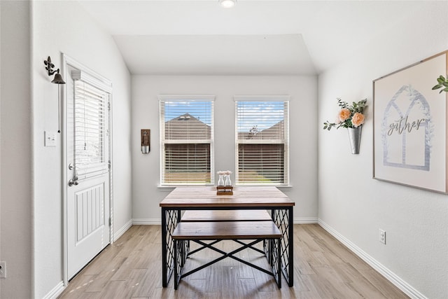 dining room featuring vaulted ceiling, baseboards, and light wood-style floors