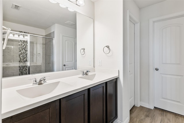 bathroom featuring visible vents, a sink, a stall shower, and double vanity