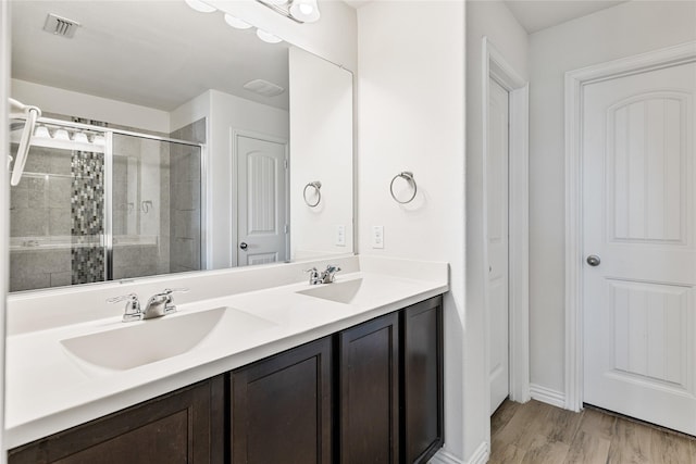 full bath with double vanity, a shower stall, visible vents, and a sink