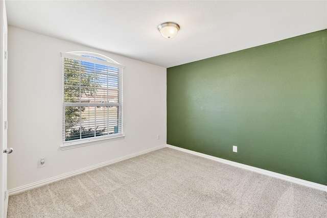 unfurnished room featuring carpet and baseboards