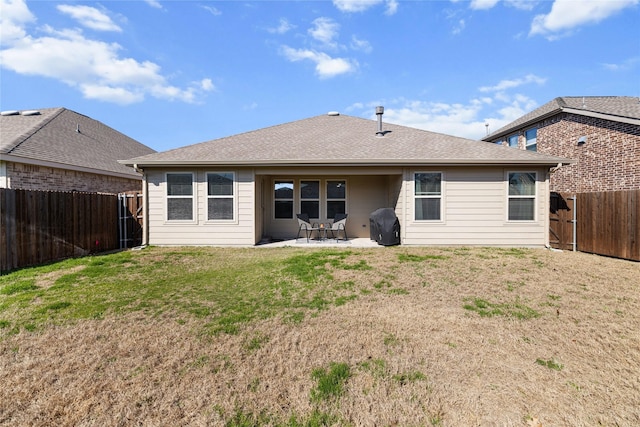 back of house with a shingled roof, a fenced backyard, a yard, and a patio