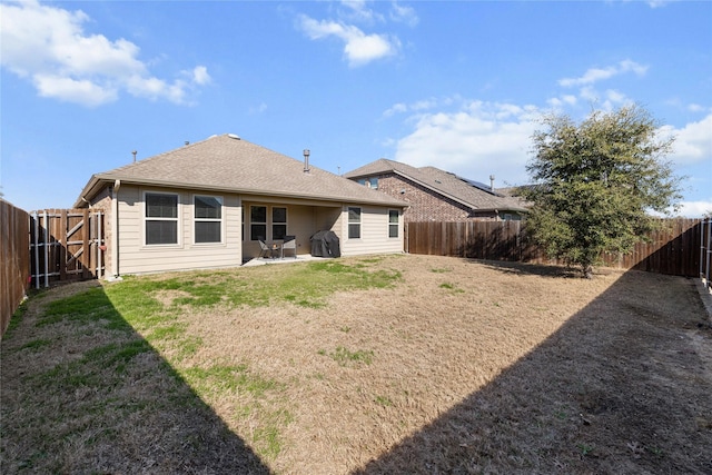 rear view of house featuring a yard, a fenced backyard, a patio, and a shingled roof