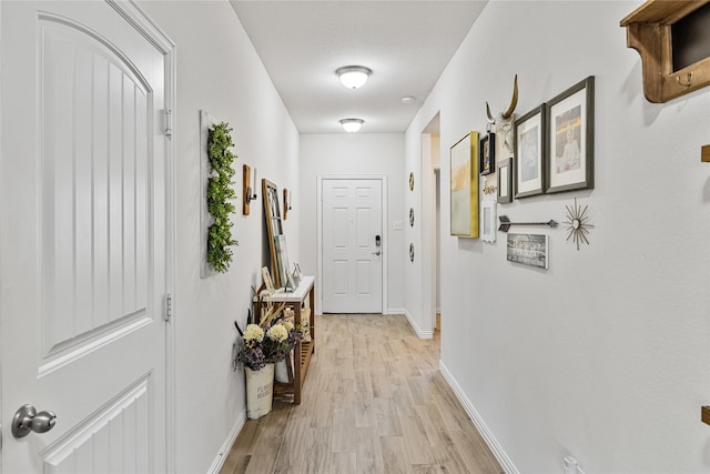 corridor with baseboards and light wood finished floors