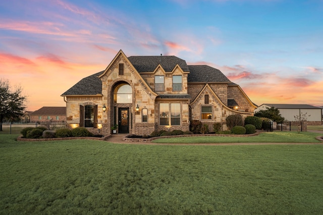 view of front facade featuring brick siding, stone siding, fence, and a front yard