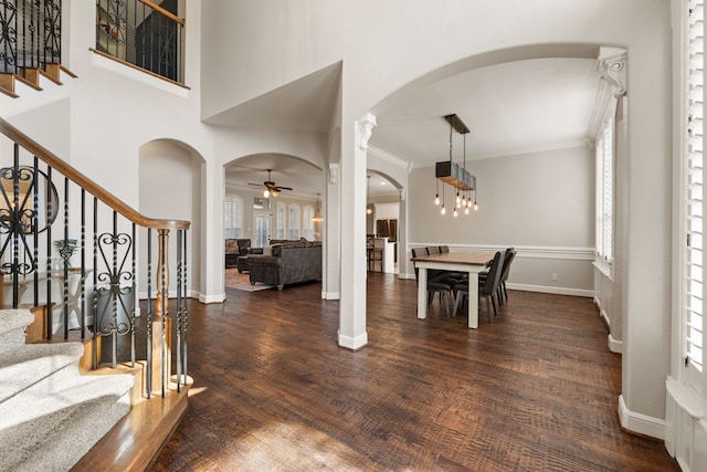 foyer entrance with arched walkways, wood finished floors, baseboards, stairs, and ornamental molding