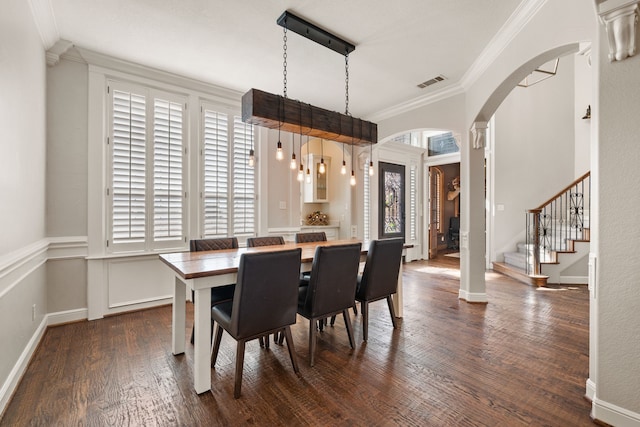 dining room with arched walkways, visible vents, stairs, dark wood finished floors, and crown molding