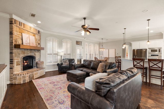 living area with dark wood-style floors, visible vents, crown molding, and a stone fireplace