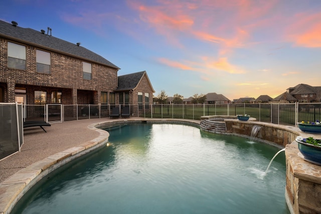 view of swimming pool with a pool with connected hot tub, fence, and a patio