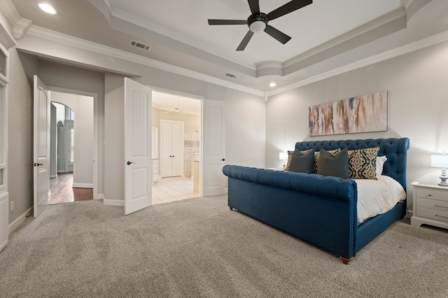 bedroom with visible vents, crown molding, a tray ceiling, and carpet flooring