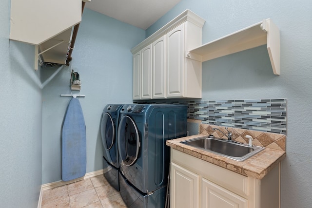 laundry area with light tile patterned floors, a sink, baseboards, cabinet space, and washer and clothes dryer