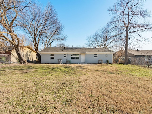 back of property with central AC unit and a yard