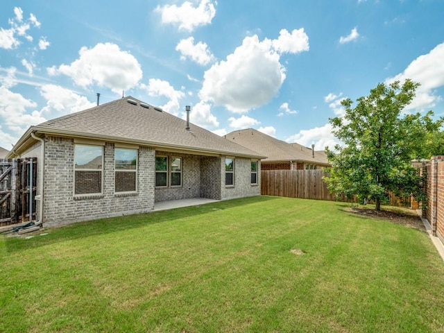 back of house with brick siding, a fenced backyard, a yard, and a patio