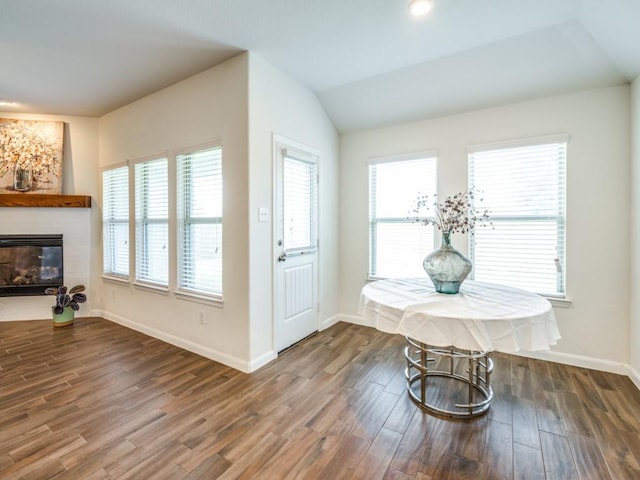 dining area with baseboards, a glass covered fireplace, lofted ceiling, and dark wood finished floors