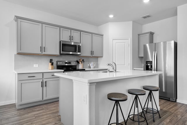 kitchen featuring light countertops, stainless steel appliances, a kitchen island with sink, and a sink