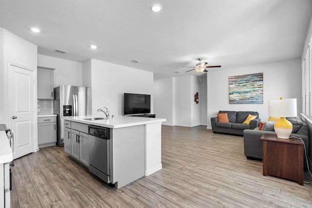 kitchen featuring gray cabinets, open floor plan, a center island with sink, and light countertops