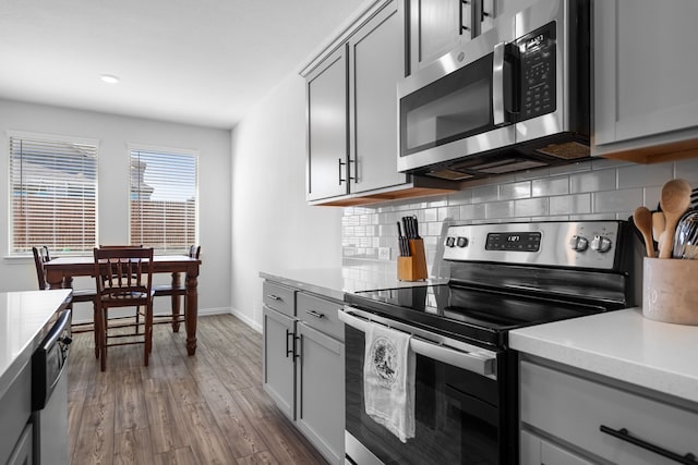 kitchen featuring light countertops, stainless steel appliances, gray cabinetry, and decorative backsplash